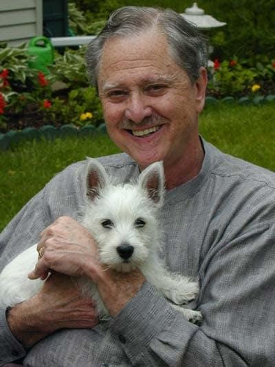 Art wearing a gray shirt, holding his West Highland Terrier Duncan.